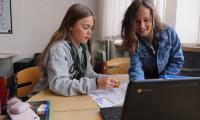 To piger i skolealderen, kigger på computer 