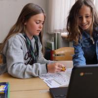 To piger i skolealderen, kigger på computer 